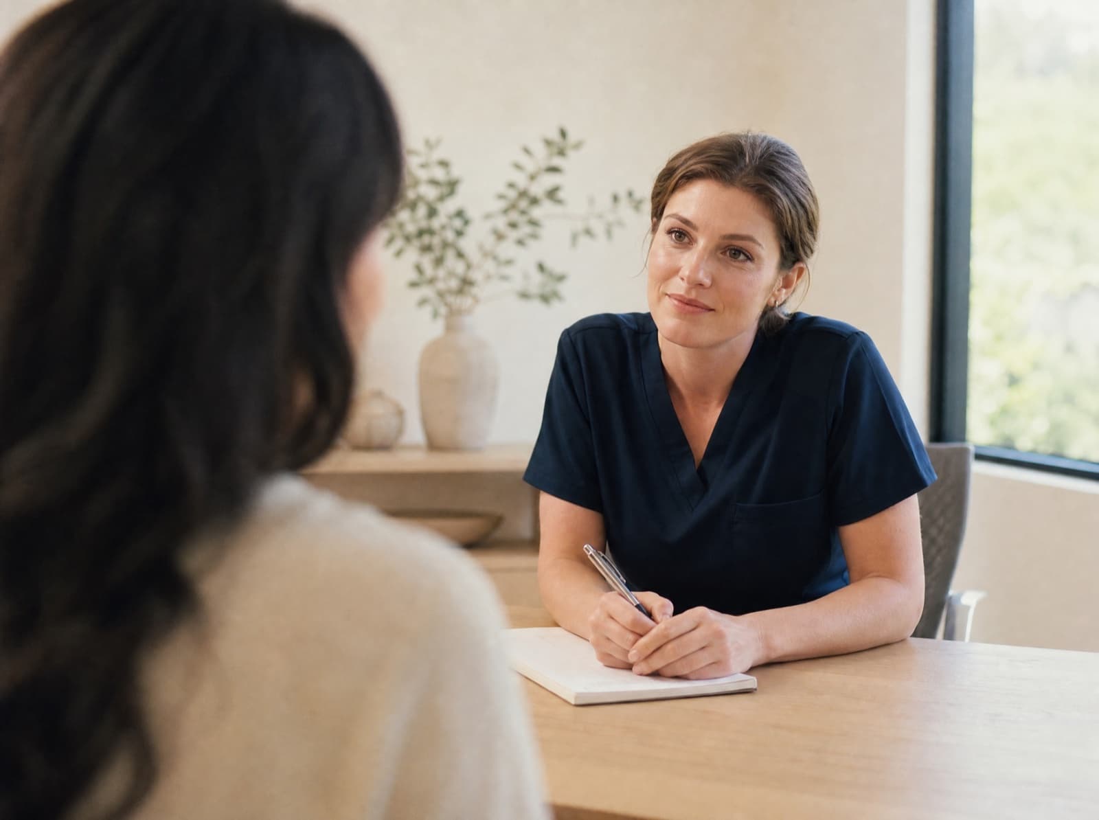 A patient and a Soza practitioner talking across a desk during a consultation